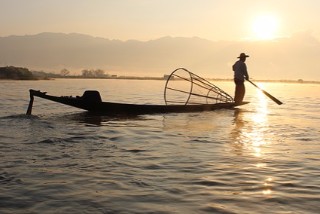 Fisherman on a boat fishing at sunset