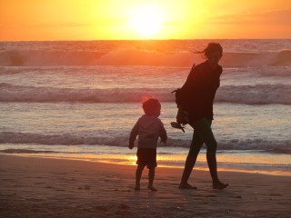 Mother and child walking on a beach at sunset